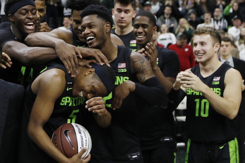 Michigan State guard Cassius Winston, front left, is hugged by teammates after Friday's game against Wisconsin in East Lansing, Mich. Winston attained the all-time Big Ten and Michigan State records. - Photo by Carlos Osorio of The Associated Press