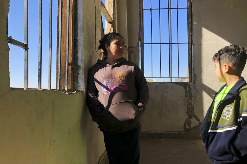 In this Jan. 11, 2020, photo, Enma Floriana chats with her 13-year-old son in the stairway of a migrant shelter in Mexicali, Mexico. The Guatemalan family is seeking asylum in a San Diego immigration court.