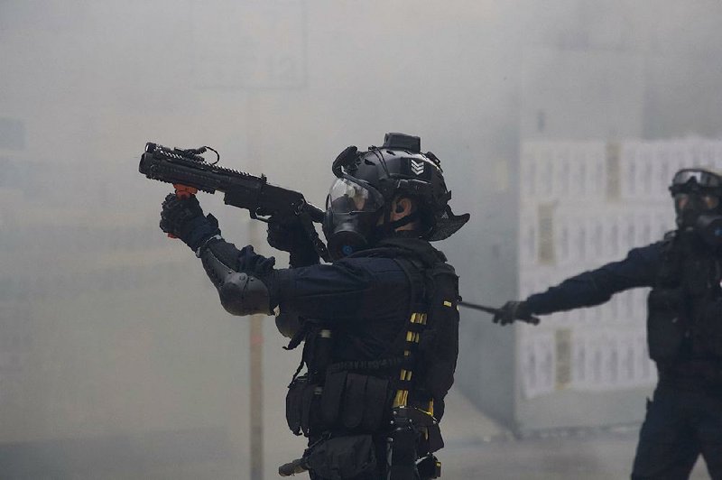 A police officer in Hong Kong uses tear gas Sunday against protesters after a demonstration turned violent. More photos at arkansasonline.com/120hongkong/.  