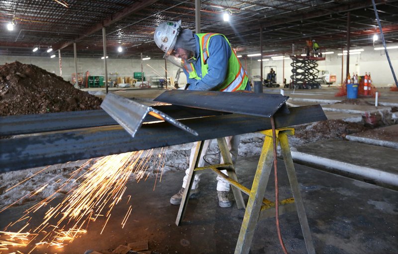 Tanner Myers with Nabholz Construction grinds the edge of angle iron for supports of roof top units Wednesday inside the new location of Ozark Natural Foods, 380 N. College Ave., in Fayetteville. The new store will feature an expanded farm and garden department, taproom and coffee bar, outdoor covered patio, a flexible sit-down space inside, to-go meals and revamped branding. Go to nwadg.com/photos for today's photo gallery. (NWA Democrat-Gazette/David Gottschalk)