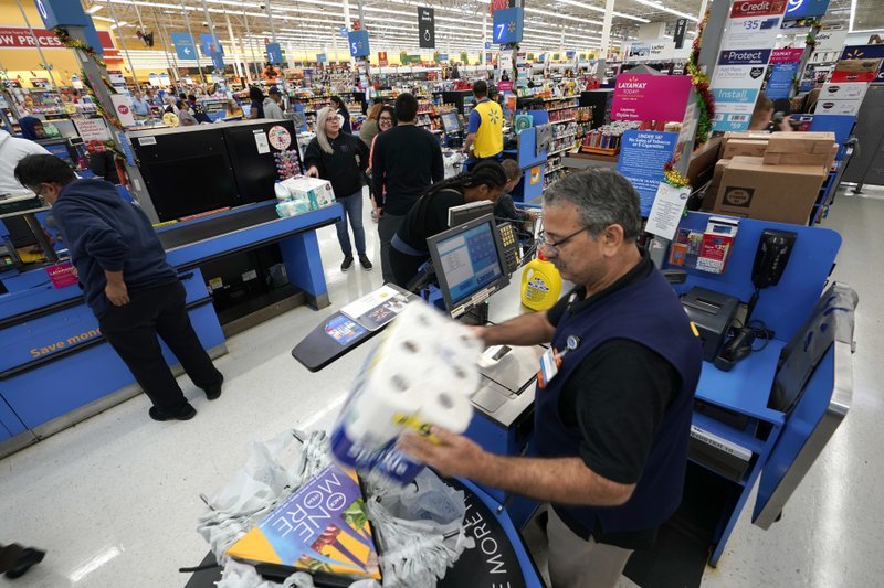 In this Nov. 9, 2018, file photo Walmart associate Javaid Vohar, right, checks out customers at a Walmart Supercenter in Houston. Walmart says it is testing higher wages for new hourly positions at 500 of its U.S. stores as part of an overall strategy to better empower its staff. (AP Photo/David J. Phillip, File)