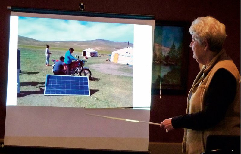 Joi Burton points out a solar panel, the motorcycle that children ride to school each week, and the ger in the background. - Submitted photo