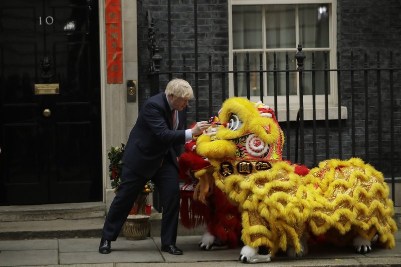 British Prime Minister Boris Johnson dots the eyes with paint Friday on a lion costume worn by performers as he welcomes members of the British Chinese community for Lunar New Year celebrations outside his residence at No. 10 Downing St. in London. Also Friday, Johnson put his signature on an exit agreement with the European Union, but with no news photographers present.  