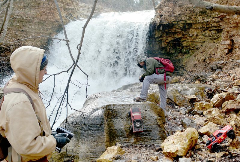 Shawn Puryear (left) attempts some tricky climbing while Smokie Adams uses a winch tethered to his shoe to climb a steep, slick rock near the Tanyard Creek waterfall in Bella Vista. (NWA Democrat-Gazette/Keith Bryant)