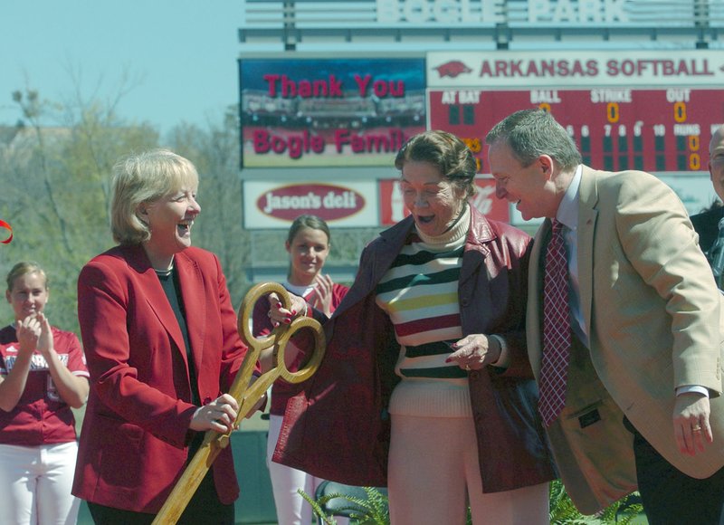 Bev Lewis (left), associate vice chancellor and executive associate AD, hands a pair of giant scissors to Marilyn Bogle (center) with Jeff Long (right), vice chancellor and director of athletics, to help cut the ribbon April 11, 2009, during the official dedication of Bogle Park, the home of the Razorback Softball team.
(Arkansas Democrat-Gazette file photo/Michael Woods)