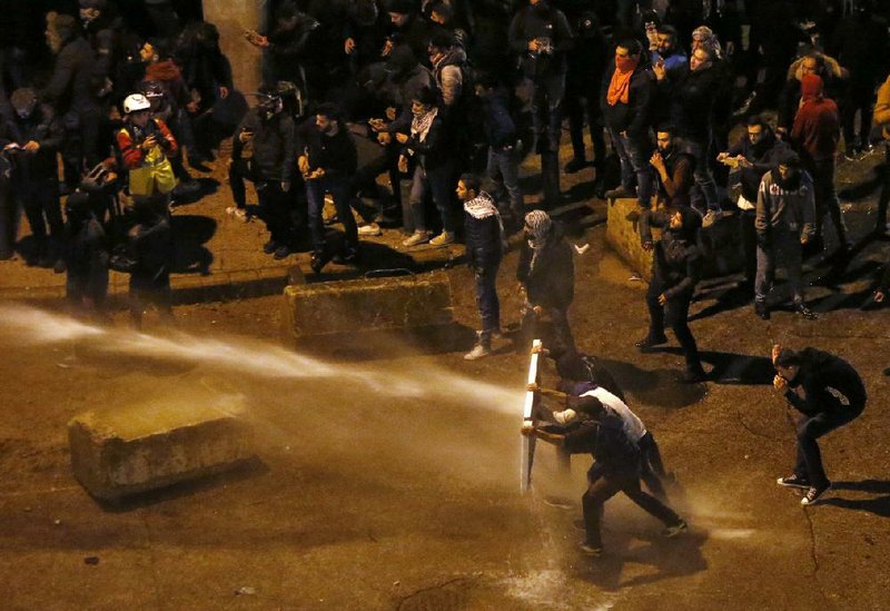 Riot police officers use water cannons and tear gas Saturday in Beirut as they battle demonstrators who stormed the central government building to protest the newly formed Cabinet. More photos at arkansasonline.com/126beirut/.
(AP/Bilal Hussein)