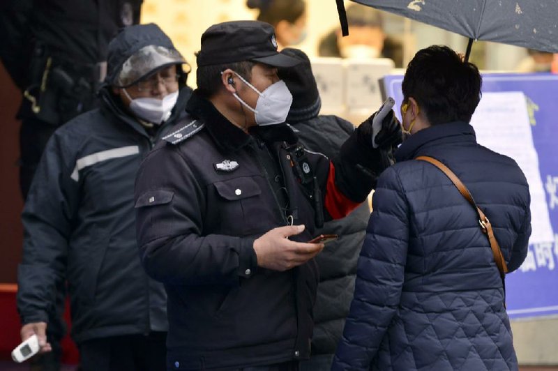 A policeman wearing a face mask takes a tourist’s  temperature at the Qinhuai scenic zone in Nanjing  in  eastern China’s Jiangsu  province, Saturday. More photos  at arkansasonline.com/126outbreak/.
(AP)
