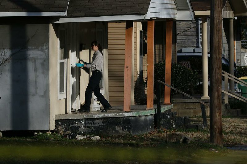 A Little Rock police crime scene investigator enters a house to collect evidence Saturday after an early morning double homicide on South Ringo Street. More photos at www.arkansasonline.com/126homicide/. 