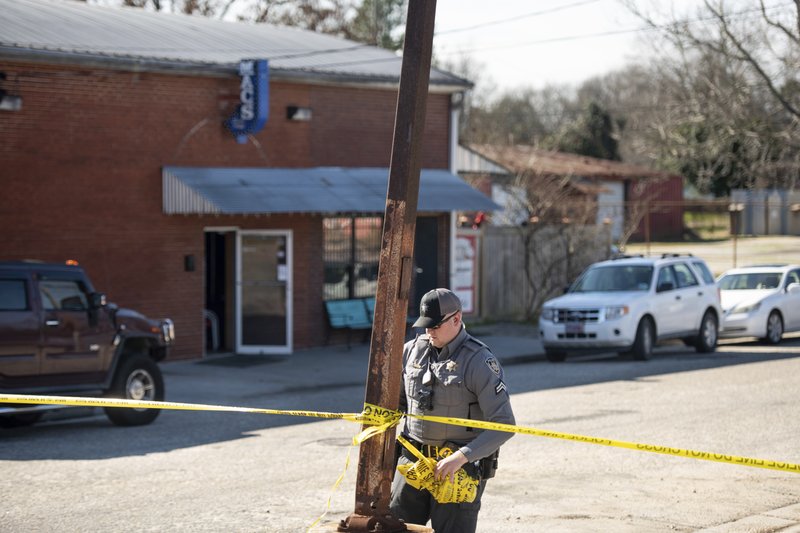 A law enforcement officer removes crime scene tape Sunday in front of Mac’s Lounge in Hartsville, S.C., hours after a shooting.  