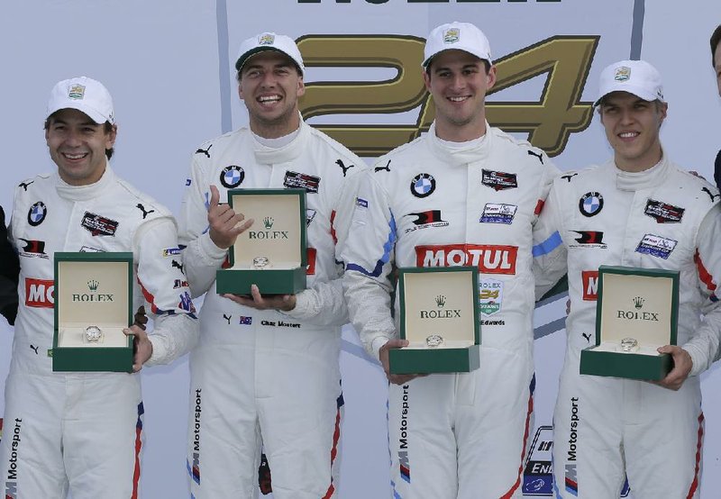 GT Le Mans class winners Augusto Farfus (from left), Chaz Mostert, John Edwards (formerly of Little Rock) and Jesse Krohn hold their Rolex watches in victory lane after winning the division at the Rolex 24-hour race at Daytona on Sunday.