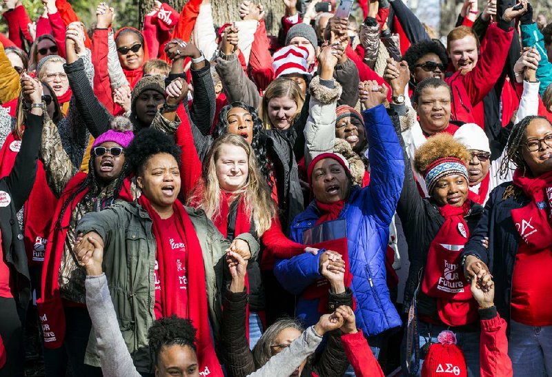 Educators and supporters raise their hands as they chant for more school funding Monday during a Virginia Education Association rally at the state Capitol’s Bell Tower in Richmond. 