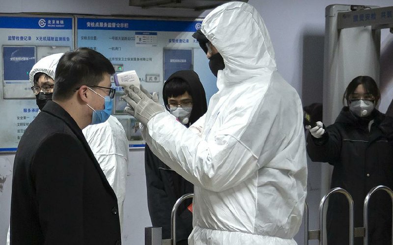 A health worker wearing a hazardous materials suit takes the temperature of a passenger Sunday at the entrance to a Beijing subway station. More photos at arkansasonline.com/127china/. 
