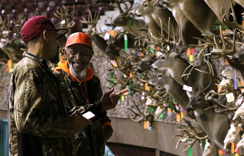 Robert Calhoun (right) talks with his son, Kendrick Calhoun, both of Lonoke, as they look at the mounted deer heads on display during the Big Buck Classic on Sunday, Jan. 26, 2020, at Barton Coliseum in Little Rock.  
See more photos at www.arkansasonline.com/127bigbuck/
(Arkansas Democrat-Gazette/Thomas Metthe)