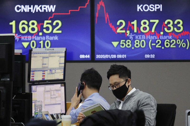 A currency trader wearing a mask watches works Tuesday at KEB Hana Bank in Seoul, South Korea. Businesses with ties to China are monitoring the coronavirus outbreak there.
(AP/Ahn Young-Joon)
