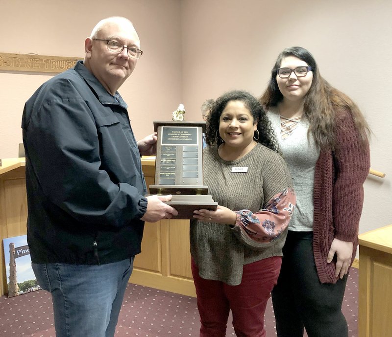 RACHEL DICKERSON/MCDONALD COUNTY PRESS Pineville Mayor Greg Sweeten presents Monica Vela (left) and Krista Tandy with the trophy for the Christmas lighting contest at the meeting of the board of aldermen on Tuesday.