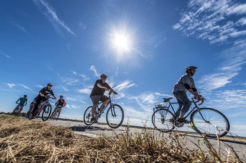 An Arkansas Parks and Tourism press photo shows bikers riding along a roadway. 