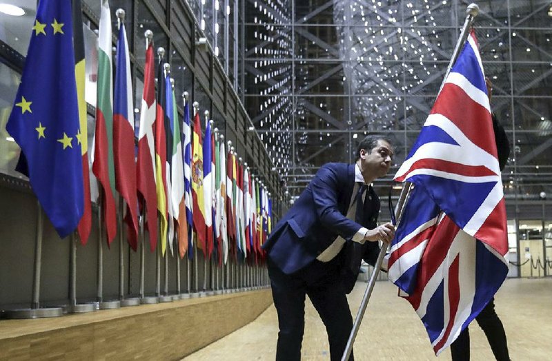 A European Union official removes the Union Jack from the atrium of the Europa building in Brussels on Friday as Great Britain prepared to end its membership after 47 years.
(AP/Olivier Hoslet)