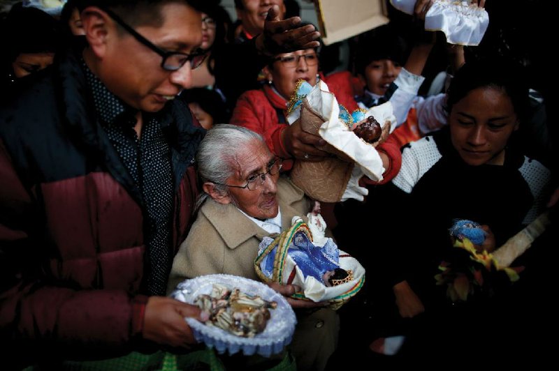 People wait their turn to have their baby Jesus dolls blessed by a priest as they leave the Three Kings Day Mass at San Francisco Church in La Paz, Bolivia. Outside the church, many parishioners went to indigenous guides to get additional blessings that come from the country’s belief in the Pachamama, or mother earth deity.