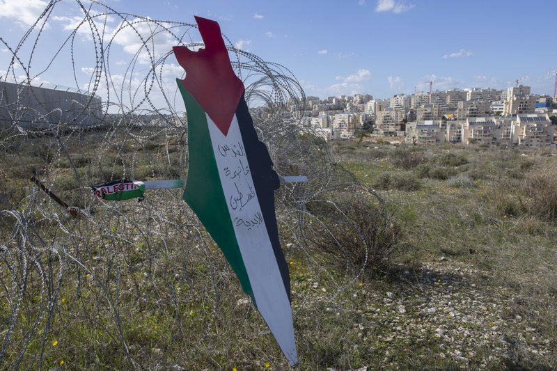 Protesters post a placard with the colors of the Palestinian flags and Arabic that reads &quot;Jerusalem is the eternal capital of Palestine,&quot; at a barbed wire surrounding the Israeli separation wall and the Israeli settlement of Mod'in Ilit, background, during a protest against Israel and the Untied States in the West Bank village of Bil'in, near Ramallah, Friday, Jan. 31, 2020. (AP Photo/Nasser Nasser)