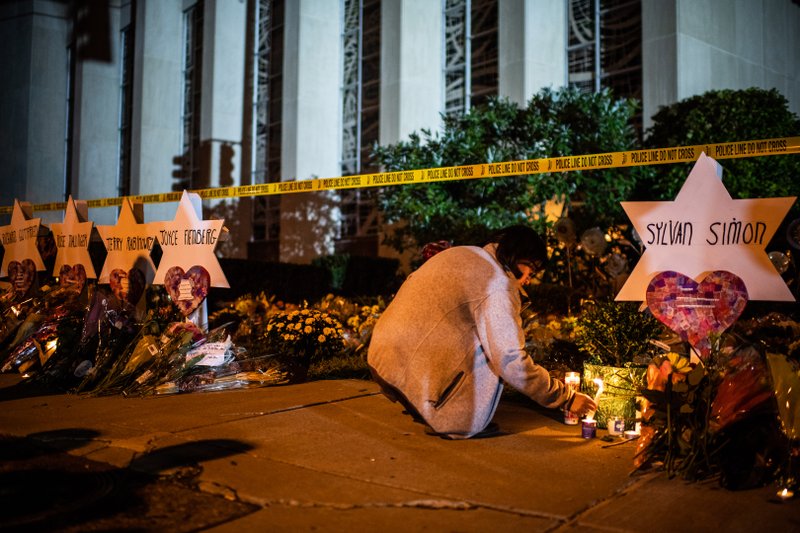 A woman leaves a candle in front of the Tree of Life Synagogue in Pittsburgh after a deadly attack there in 2018. MUST CREDIT: Washington Post photo by Salwan Georges