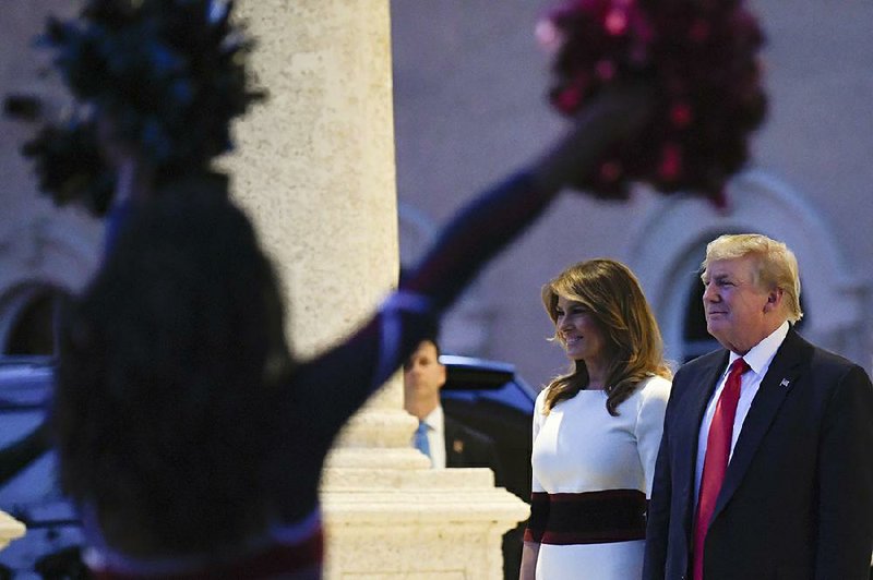 President Donald Trump and first lady Melania Trump watch as the Florida Atlantic University Marching Band performs Sunday during a Super Bowl party at the Trump International Golf Club in West Palm Beach, Fla.
