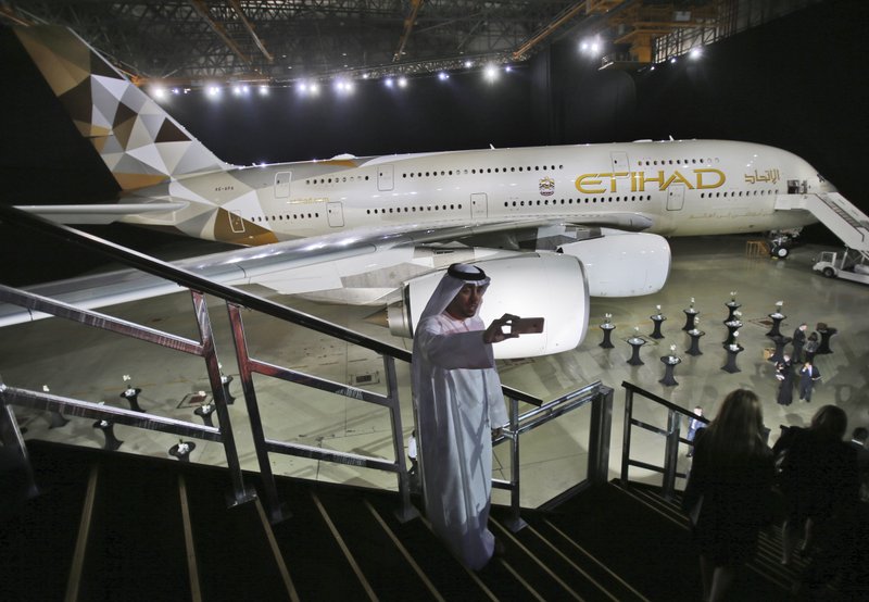 FILE- In this Thursday, Dec. 18, 2014 file photo, an Emirati man takes a selfie in front of a new Etihad Airways A380 in Abu Dhabi, United Arab Emirates. Abu Dhabi's long-troubled Etihad Airways said Tuesday, Feb. 4 2020, it would sell 38 aircraft to an investment firm and a leasing company in a deal valued at $1 billion, the latest cost-cutting measure by the United Arab Emirates' national carrier. (AP Photo/Kamran Jebreili, File)
