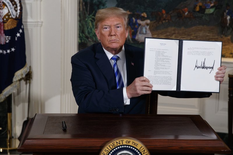 FILE - In this May 8, 2018 file photo, President Donald Trump shows a signed Presidential Memorandum after delivering a statement on the Iran nuclear deal from the Diplomatic Reception Room of the White House. The decision Tuesday, Jan 14, 2020, by European nations to trigger a dispute resolution mechanism in the Iran nuclear deal marks the latest step in the unraveling of the accord, which began when President Donald Trump walked away from the agreement and began restoring sanctions on Iran. (AP Photo/Evan Vucci, File)