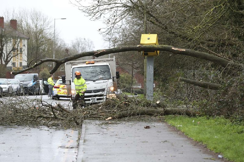 Workmen clear away a fallen tree Sunday in Tilehurst, England, an area hit by Storm Ciara. More photos at arkansasonline.com/210ciara/.