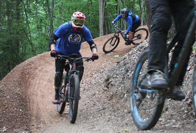 From back, Rodney James, Mark Lovett and Traci Berry, trails coordinator for Visit Hot Springs, ride Ragnarok trail in the Northwoods Trails System in May 2019. - File photo by Jami Smith of The Sentinel-Record
