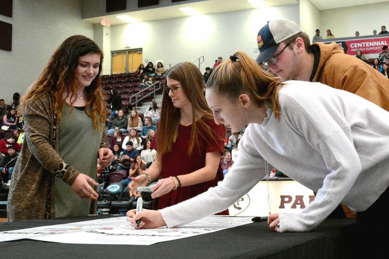Janelle Jessen/Siloam Sunday Seniors Maci Davis (left), Taylor Davis, Jaslyn Dalrymple and Alex Dabb sign a poster symbolizing their commitment to go on to post-secondary education during the Siloam Springs High School's first career and technical education signing ceremony on Tuesday.