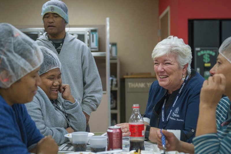 In this October 2018 photo provided by Tyson Foods, Karen Diefendorf, second right, director of Chaplain Services at Tyson Foods, talks with employees at the company's Berry St. poultry plant in Springdale, Ark. The company deploys a team of more than 90 chaplains to comfort and counsel employees at its plants and offices. The program began in 2000. (Logan Webster/Tyson Foods via AP) story.lead_photo.caption