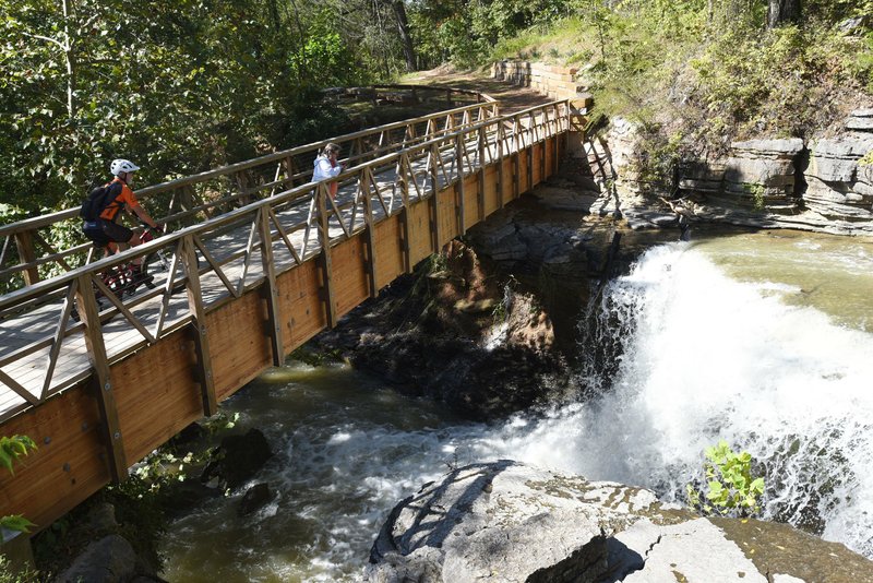 In this 2019 file photo, a biker and hiker admire a waterfall near Lake Ann in Bella Vista along a section of the Back 40 trail system.