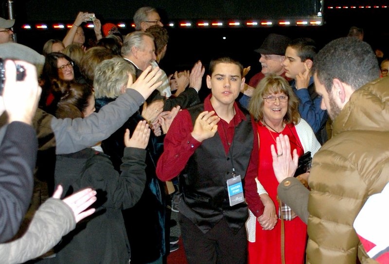 Janelle Jessen/Herald-Leader Hayden Ford gives out high-fives as he walks the red carpet, greeted by a cheering crowd, at Siloam Springs' first Night to Shine on Friday evening.