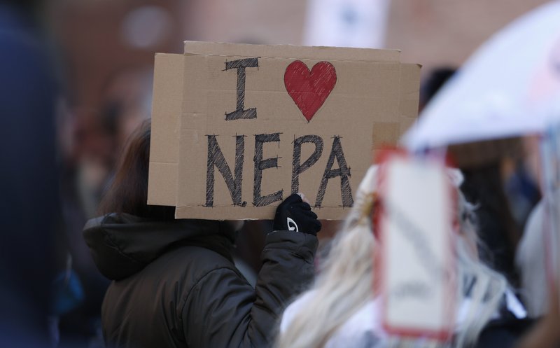 Joan Lutz of Boulder, Colo., waves a placard at a rally of advocates to voice opposition to efforts by the Trump administration to weaken the National Environmental Policy Act, which is the country's basic charter for protection of the outdoors on Tuesday, Feb. 11, 2020, in Denver. (AP Photo/David Zalubowski)