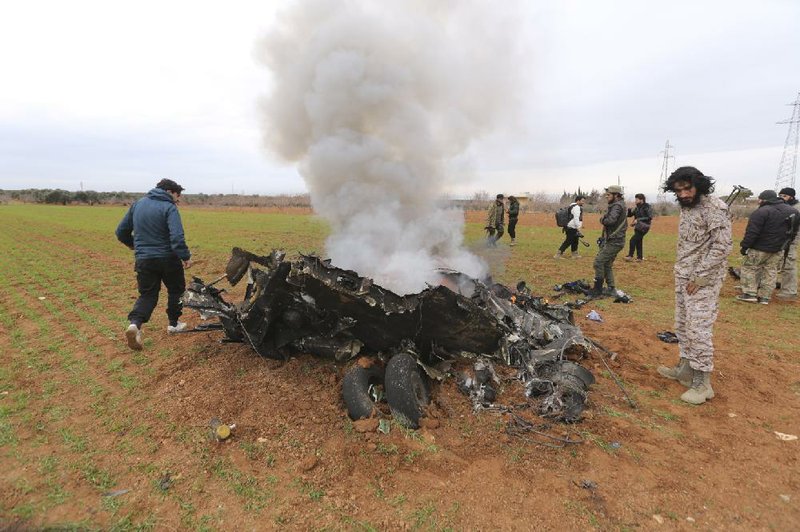 Rebel fighters examine the wreckage of the Syrian government helicopter that they shot down Tuesday in Idlib province. More photos at arkansasonline.com/212syria/.
(AP/Ghaith Alsayed)