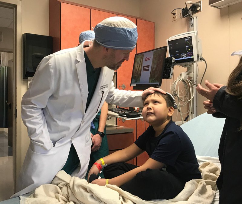 Dr. Gresham Richter greets 8-year-old Mikhail in advance of a procedure at Arkansas Children's Hospital. a la Carte, hosted March 6 by the Northwest Arkansas Circle of Friends, will benefit Arkansas Children's Northwest. (Arkansas Democrat-Gazette File Photo/Kat Stromquist)