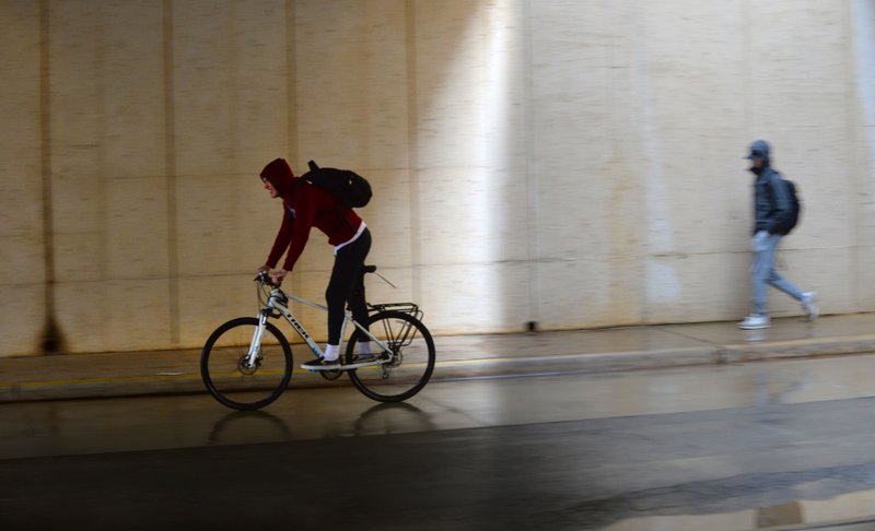 A cyclist rides quickly past Wednesday in the rain along Garland Avenue beneath the Arkansas Union on the University of Arkansas campus in Fayetteville. Chances of more rain diminish heading into the weekend according to the National Weather Service. Go to nwaonline.com/200213Daily/ for today's photo gallery. (NWA Democrat-Gazette/Andy Shupe) story.lead_photo.caption