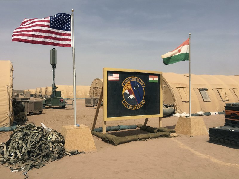 FILE- In this file photo taken Monday, April 16, 2018, a U.S. and Niger flag are raised side by side at the base camp for air forces and other personnel supporting the construction of Niger Air Base 201 in Agadez, Niger. As extremist violence grows across Africa, the United States is considering reducing its military presence on the continent, a move that worries its international partners who are working to strengthen the fight in the tumultuous Sahel region. (AP Photo/Carley Petesch, File)