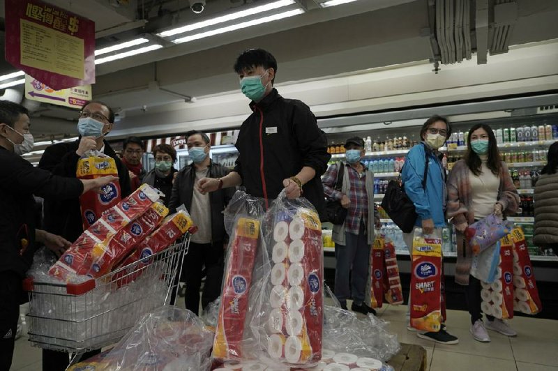 Masked customers line up to buy toilet paper Friday in a Hong Kong supermarket. More photos are available at arkansasonline.com/215virus/
(AP/Kin Cheung)