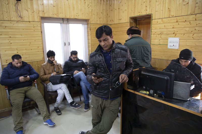 In this Jan. 30, 2020, photo, Kashmiri journalists browse the internet on their mobile phones inside the media center set up by government authorities in Srinagar, Indian controlled Kashmir. Six months after India stripped restive Kashmir of its semi-autonomy, enforcing a total communications blackout, it has restored limited internet at slow speeds with access only to government-approved websites. Since Modi came into power in 2014, the internet has been suspended more than 365 times in India, according to the global digital rights group Access Now. (AP Photo/ Dar Yasin)