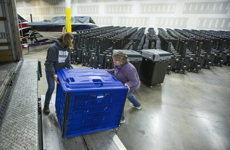 Julie Hall (left) and Vivki Penny with the Benton County Election Commission load voting machines and other equipment Thursday into a truck at the Benton County Election Commission office in Rogers. Staff began distributing equipment Thursday to the 36 vote centers for the March 3 primary election. Go to nwaonline.com/200214Daily/ for today's photo gallery. (NWA Democrat-Gazette/Ben Goff)