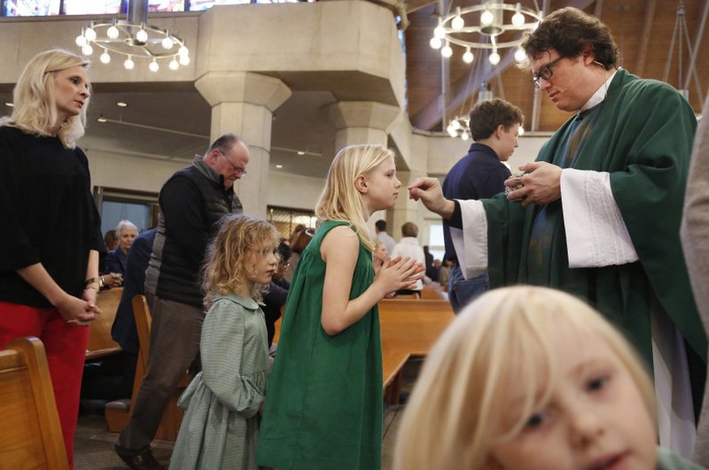 In this Feb. 9 photo, the Whitfield family, wife Alli, left, daughters Zoe-Catherine, 5, second from left, and Maggie, 9, second from right, receive communion from their dad and husband, The Rev. Joshua Whitfield, right, during Sunday Mass at St. Rita Catholic Community in Dallas. In 2009 the Whitfields, who were Episcopalian, converted to Catholicism. - AP Photo/Jessie Wardarski