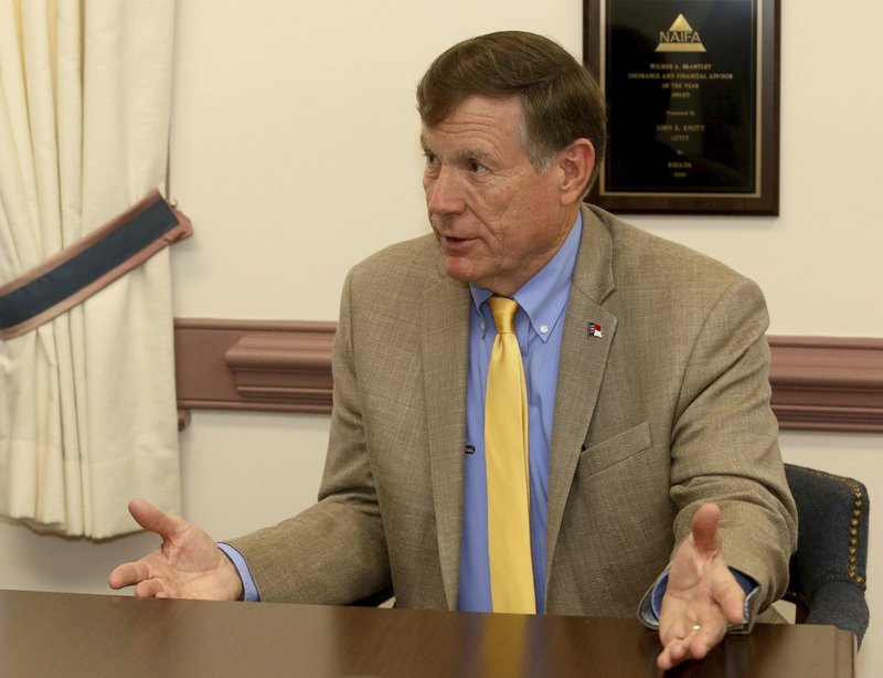 FILE -In this July 10, 2019, file photo, North Carolina State Insurance Commissioner Mike Causey talks with State Farm insurance agent John Knott at Knott's office in Rocky Mount, N.C. A insurance company magnate and two associates, accused of fraud conspiracy and bribery counts related to an alleged scheme of giving up to $2 million in campaign money to help Insurance Commissioner Mike Causey in exchange for Causey pushing aside a senior deputy, go on trial next week. (Alan Campbell/Rocky Mount Telegram via AP, File)