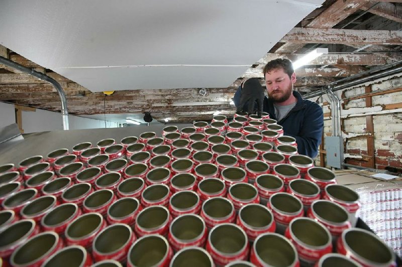 Jason Kramer of Fayetteville feeds cans into the canning line at the Black Apple cidery in Springdale earlier this month. More photos at arkansasonline.com/216cider/.
(NWA Democrat-Gazette/J.T. Wampler)