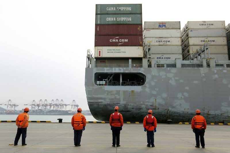 In this early February photo, workers watch a container ship arrive at a port in Qingdao in east China’s Shandong province. 
(Courtesy of Chinatopix via AP)