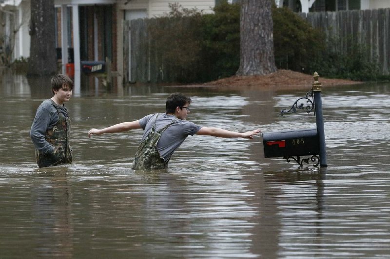 Blaine Henderson (right) reaches to tag a mailbox Sunday as he and his friend Jonah Valdez play in floodwaters from the Pearl River in northeast Jackson, Miss. More photos at arkansasonline.com/217jackson/.
(AP/Rogelio V. Solis)