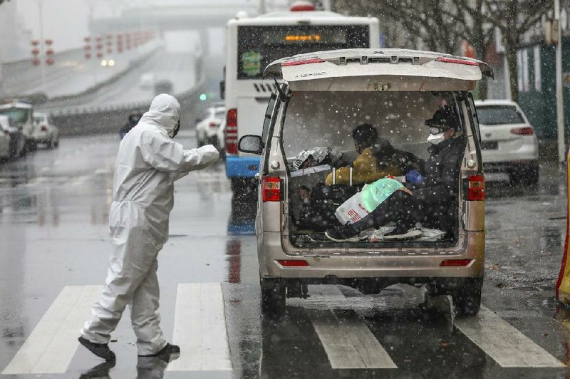 A worker in a protective suit transports patients Saturday in the back of a van to a tumor hospital in Wuhan, China, that was newly designated to treat coronavirus victims. More photos at arkansasonline.com/216virus/.
(AP)