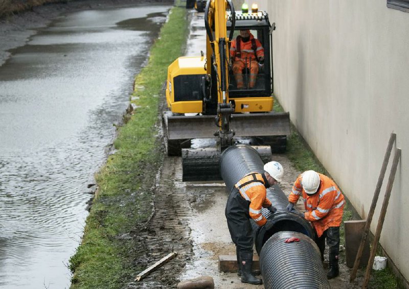 Workers in Mytholmroyd village in England prepare flood defenses Saturday as a winter storm approaches. More photos at arkansasonline.com/216dennis/.
(AP/Danny Lawson)