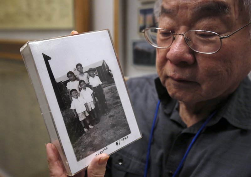 In this photo taken Feb. 11, Les Ouchida holds a 1943 photo of himself, front row, center, and his siblings taken at the internment camp his family was moved to, as he poses at the permanent exhibit titled "UpRooted Japanese Americans in World War II" at the California Museum in Sacramento, Calif. Ochida, who is a docent for the exhibit, and his family were forced to move in 1942 from their home near Sacramento to a camp in Jerome, Arkansas. Assemblyman Al Muratsuchi, D-Torrence has introduced a resolution to apologize for the state's role in carrying out the federal government's internment of Japanese-Americans. A similar resolution will be brought up before the state Senate by Sen. Richard Pan, D-Sacramento. - AP Photo/Rich Pedroncelli