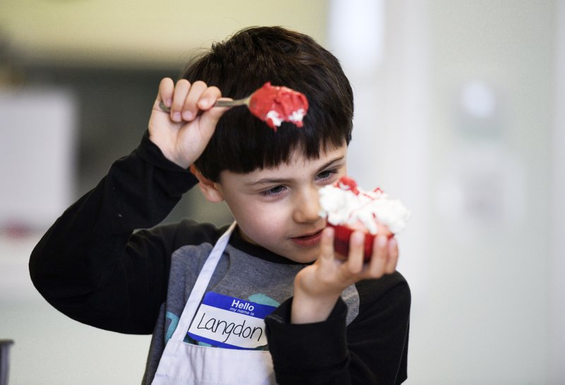Langdon Stabach, 6, of Rogers reacts Monday as he decorates a cupcake, during a cooking class for kids at Young Chefs Academy in Rogers. The academy held a one-day patriotic, cooking workshop. The kids made sloppy joes, celebration stick pretzels with frosting and patriotic cupcakes. The academy started family cooking classes every Friday night as well and will hold its next camp during spring break. Go to nwaonline.com/200218Daily/ for today's photo gallery. (NWA Democrat-Gazette/Charlie Kaijo)